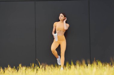 Bir şişe suyla. Spor giyimli genç bir kadının dışarıda spor seansı var..