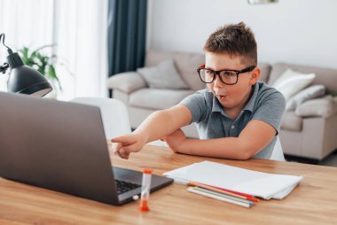 Küçük çocuk evde dizüstü bilgisayar kullanarak online dersler alıyor..