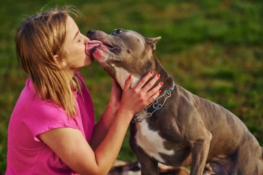 Dışarıda, sahada. Normal elbiseli kadın pitbull 'la birlikte..