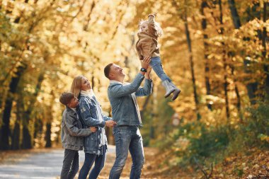 Dört kişi. Mutlu aile, sonbahar zamanı parktadır..