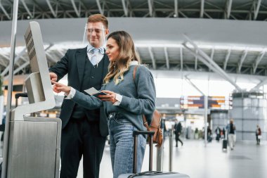 Erkek işçi kadına yardım ediyor. Genç bayan turist gündüz vakti havaalanında..