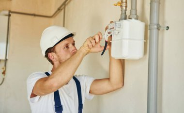 Modern teknolojiler. Gündüz vakti inşaatta üniformalı genç bir adam çalışıyor..