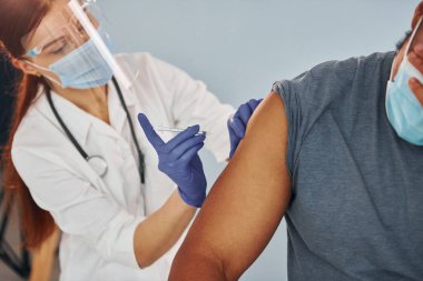 Kadın doktor, hastanedeki Afrikalı Amerikalı adama iğne yapıyor..