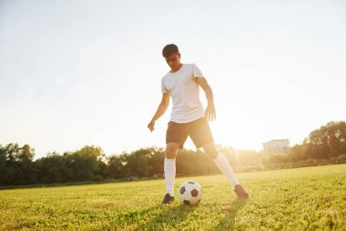 Güzel güneş ışığı. Genç futbolcu spor sahasında antrenman yapıyor..