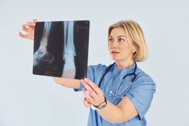 Röntgen tutuyor. Üniformalı ve steteskoplu orta yaşlı profesyonel kadın doktor..