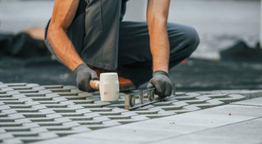 Açık havada iş. Gündüz vakti inşaatta üniformalı genç bir adam çalışıyor..