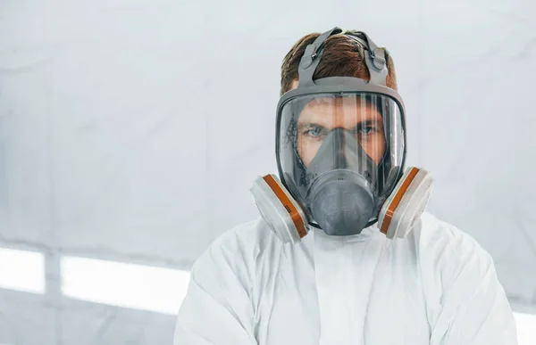 Portrait of man in the protective mask. Worker in uniform is in the auto service.