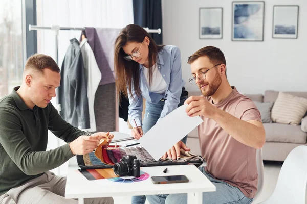 Working with cloth. Having conversation. Group of people works in the office.