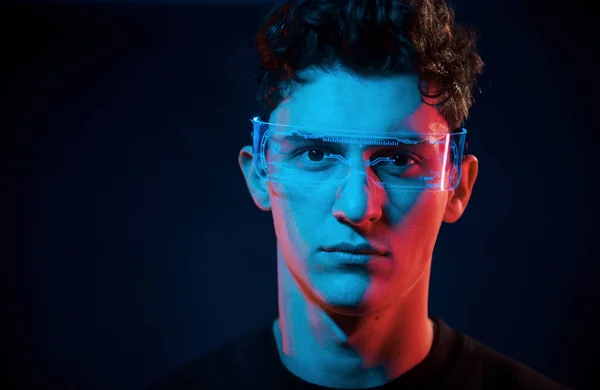 Close up portrait. Neon lighting. Young european man is in the dark studio.