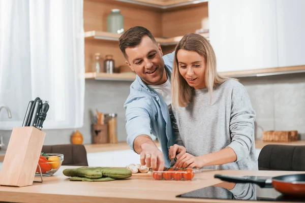 Cute people. Couple preparing food at home on the modern kitchen.