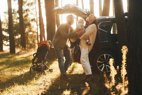 太陽の光が背景に 父と母と娘の幸せな家族が森の中にいる — ストック写真