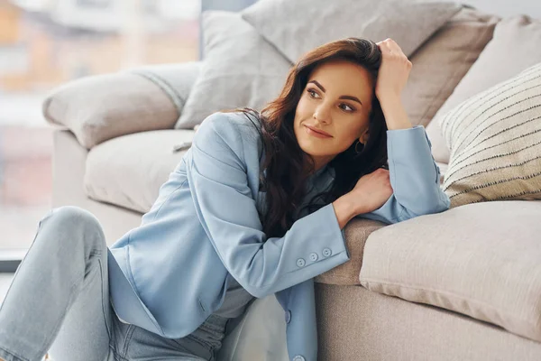 Domestic room. European woman in fashionable stylish clothes is posing indoors.