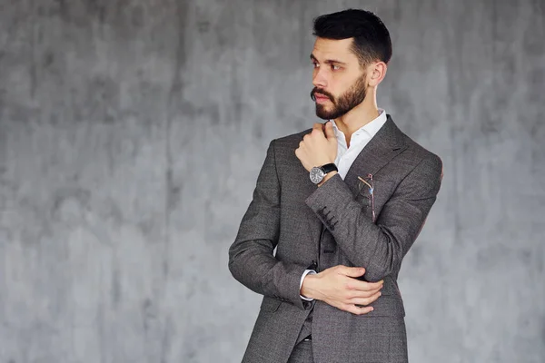 灰色の背景に立っている 室内でスーツを着た若いスタイリッシュなビジネスマン 成功の概念 — ストック写真