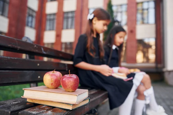 Assis Lisant Deux Écolières Sont Dehors Près Bâtiment École — Photo