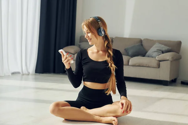 Sitting Holding Smartphone Woman Sportive Clothes Doing Yoga Indoors — Stock Photo, Image