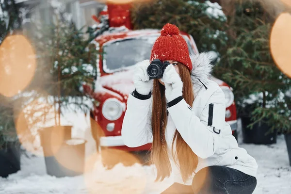 手にカメラを持つ 幸せな若い女性が屋外に立ってクリスマス休暇を祝う — ストック写真