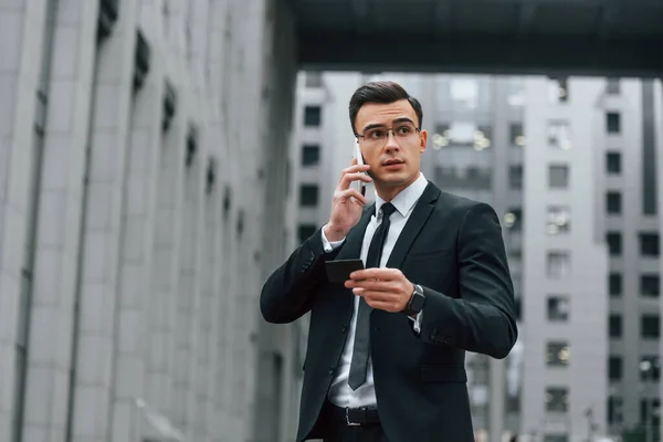用电话穿着黑色西装打领带的商人在城市的户外 — 图库照片