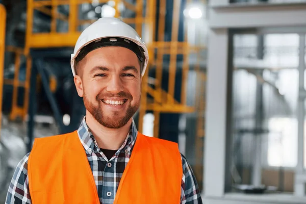 Portrait of construction worker in uniform is in the factory.