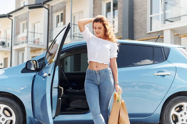 After the mall. Young woman in casual clothes with her electromobile outdoors at daytime.