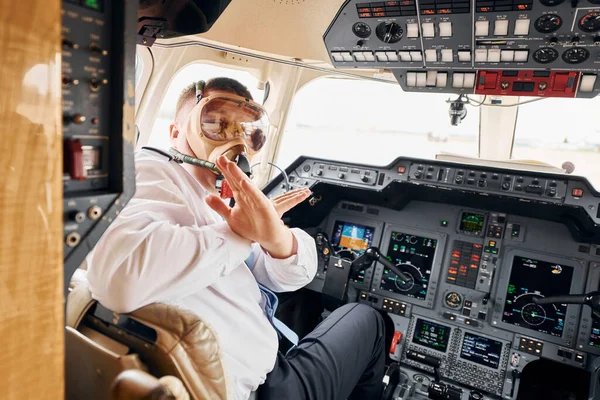 In oxygen mask. Pilot in formal wear sits in the cockpit and controls airplane.