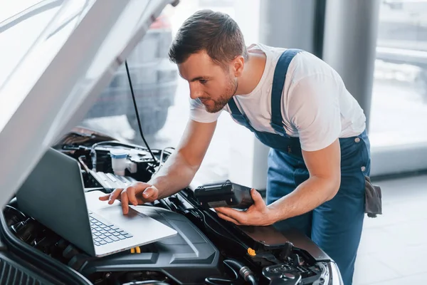 Uses Laptop Young Man White Shirt Blue Uniform Repairs Automobile — Stock Photo, Image