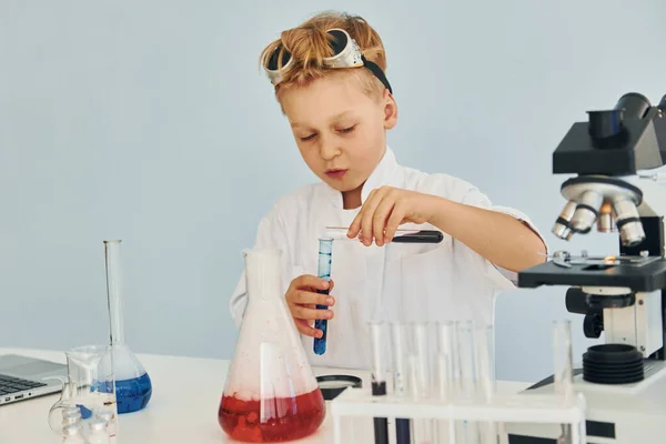 用试管穿着外套的小男孩在实验室里用设备扮演科学家 — 图库照片
