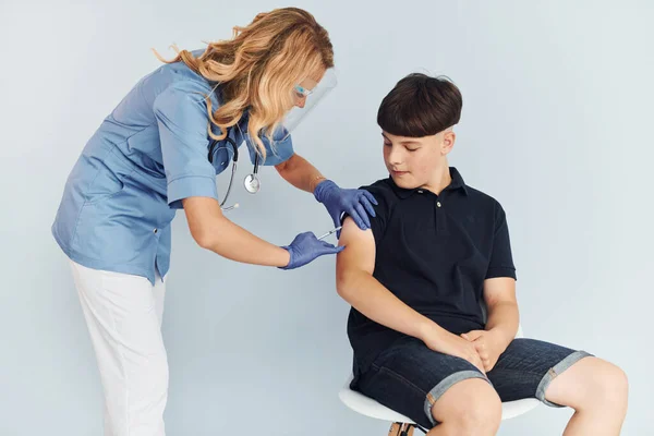 穿制服的医生给穿黑衬衫的男孩注射疫苗 — 图库照片
