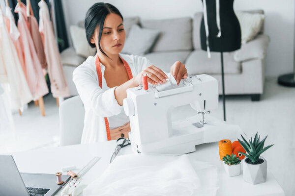 Работа с помощью швейной машинки. Швея в своем кабинете, в другой одежде..