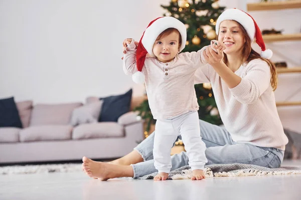 戴着圣诞礼帽妈妈和她的小女儿一起呆在家里 — 图库照片