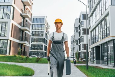 Tamamlanmış binalar. Gündüz vakti inşaatta üniformalı genç bir adam çalışıyor..