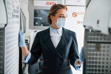 Maskeli. Yolcu uçağında çalışan genç hostes..