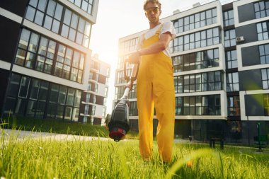 Güzel güneş ışığı. Bahçede çimleri çim biçen bir adam var..