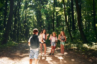 Güzel doğa. Çocuklar seyahat ekipmanlarıyla ormanda geziniyorlar..