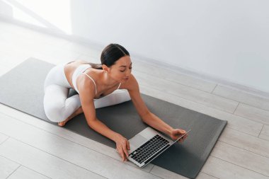 Yoga minderinde. İnce vücutlu beyaz kadın gündüz vakti evdedir..