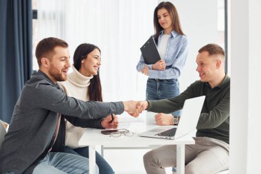 Ofiste dört kişi masa başında kapalı oturarak çalışıyor..