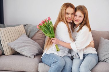 Tatilde çiçekler. Genç anne ve kızı gündüz vakti evdeler..