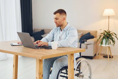 Laptop masada. Tekerlekli sandalyedeki engelli evde..