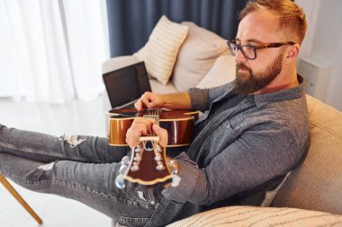 Pratik yaparken iyi vakit geçiriyorum. Gündelik giysiler içinde ve akustik gitarlı bir adam içeride..