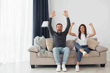 Yeni dairenin mutlu sahipleri kanepede oturuyor..