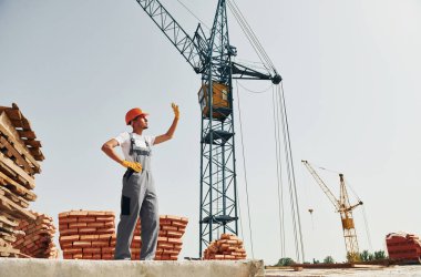 Birisiyle iletişim kurmak. Üniformalı genç inşaat işçisi tamamlanmamış binada meşgul..