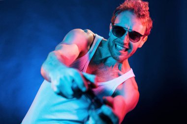 Eğleniyorum. Neon ışıkları. Genç Avrupalı adam karanlık stüdyoda..