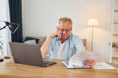 Dizüstü bilgisayarla çalışıyor. Güzel giyimli büyük adam evde..