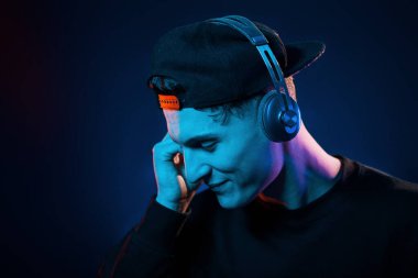 Adam kulaklık kullanıyor. Neon ışıkları. Genç Avrupalı adam karanlık stüdyoda..