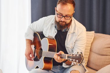Rahatlamış hissediyorum. Gündelik giysiler içinde ve akustik gitarlı bir adam içeride..
