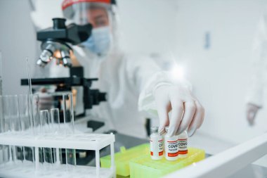 Koruyucu üniformalı kadın tıp çalışanları COVID-19 aşısı üzerinde çalışıyorlar..