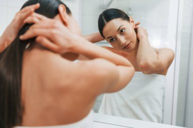 Cildine dikkat ediyor. İnce vücutlu beyaz kadın gündüz vakti evdedir..