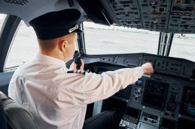 Resmi kıyafetli pilot kokpitte oturur ve uçağı kontrol eder..