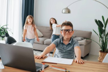 Çocuk masanın yanında oturuyor. Çocuklar gündüz vakti evlerinde eğleniyorlar..