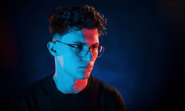 Adam düşünüyor. Neon ışıkları. Genç Avrupalı adam karanlık stüdyoda..