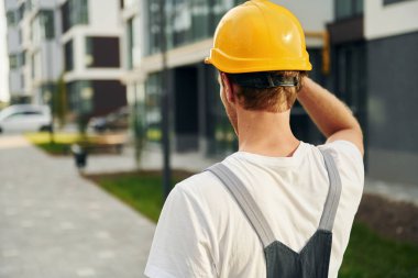 Dikiz aynası. Gündüz vakti inşaatta üniformalı genç bir adam çalışıyor..